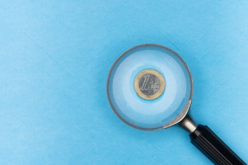 A magnifying glass resting on a 1 euro coin.