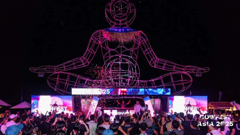 Concert and night show at the Coinfest Asia 2025 in Bali, featuring a luminous statue in human shape and an animated crowd.
